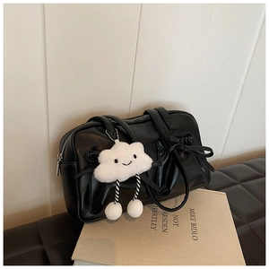 Detail of matte black bowling bag with leather bows and a white cloud plush charm