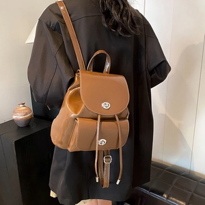 Detalle de mochila de charol marrón con cierre de broche plateado y cordón ajustable
