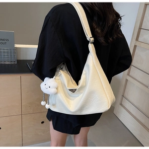 Detail of a large off-white pleated tote bag with a plush cloud charm and metal logo