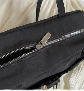 Close-up of smooth silver metal zipper on premium black textured shoulder bag fabric