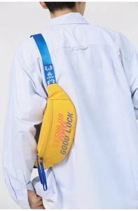 Detail of yellow street-style waist bag with contrast blue strap and lettering