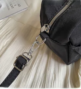 Macro shot of silver metal zipper and lobster clasp detail on a black pleated bag