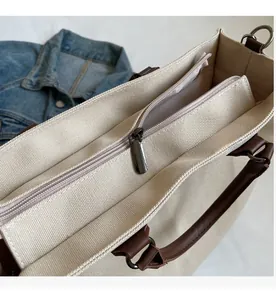 Detailed close-up of smooth metal zipper and leather handle on a canvas tote bag