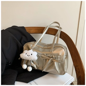 Detailed shot of champagne gold shiny tote bag with bow detail and plush cloud charm