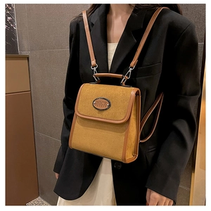 Detail of vintage suede backpack featuring a round brand logo and brown leather piping