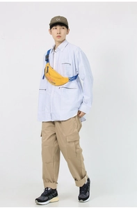 Full body shot of a male model wearing a yellow crossbody bag with casual street outfit