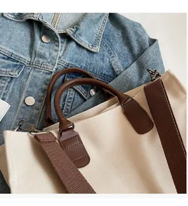 Detail of canvas tote bag with brown leather handles and strap on denim jacket