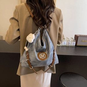 Detail of grey-blue canvas hobo bag with brown leather trim and white cloud charm