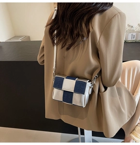 Detail of woven denim and silver leather crossbody bag shown on a model in beige blazer