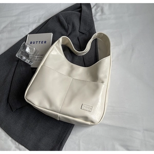 Close-up of cream glossy tote bag with dual front pockets and fashion leather label