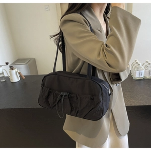 Detailed view of black pleated underarm bag with drawstring design and dual straps