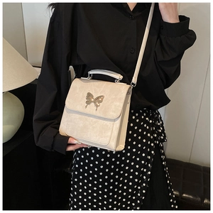 Détail d'un sac en cuir beige élégant avec fermoir papillon doré et bandoulière