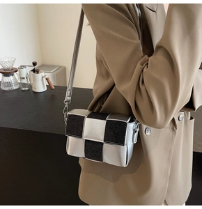 Detailed view of silver and black woven crossbody bag styled on a minimalist model
