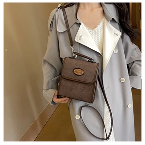 Close-up of brown suede crossbody bag with NICE FASHION logo and leather handle strap