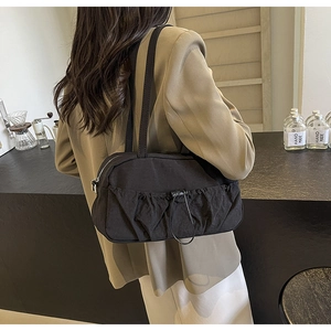Detail of black pleated shoulder bag with adjustable drawstrings worn by a model