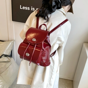 Detalle de mochila de cuero brillante burdeos con cierre de giro plateado y cordón