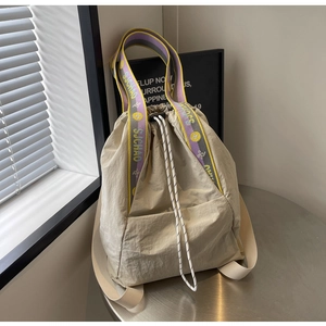 Primer plano de mochila beige con cordón y correas de hombro de jacquard SJCHAO