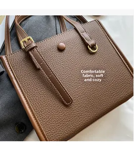 Detailansicht der braunen Handtasche mit Lychee-Lederstruktur und goldener Metallschnalle
