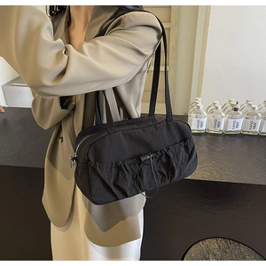 Detail of black pleated shoulder bag with adjustable drawstring on nylon fabric