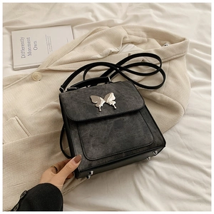 Détail d'un sac à dos vintage gris avec boucle papillon argentée et finition mate