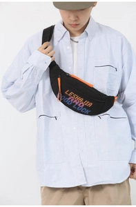 Close-up of black crossbody bag with colorful embroidery and bright orange zippers