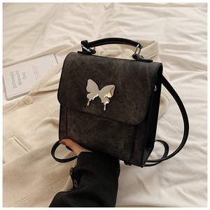 Détail du sac bandoulière gris avec papillon argenté sur un fond en tissu doux