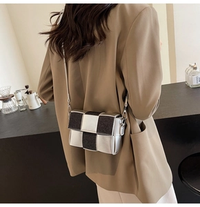 Detail view of the silver and black woven crossbody bag styled on a model in a minimal setting
