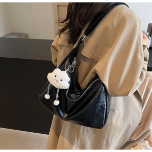 Détail du grand sac cabas noir brillant avec texture plissée et charm en peluche blanc