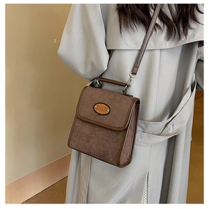 Close-up of brown suede crossbody bag with top handle and NICE FASHION leather patch