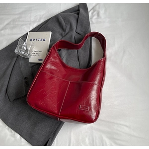 Detail of red oil-wax leather tote with white stitching and stylish fashion label