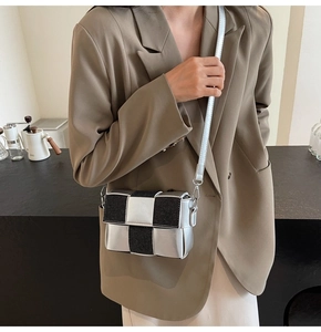 Chic silver and black woven crossbody bag shown with a tan blazer on a model