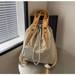 Detalle de un bolso tipo cubo con cordón en nailon y asa de tejido con diseño deportivo