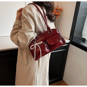 Détail du sac oreiller en cuir verni bordeaux avec poches avant et breloque nœud perlé