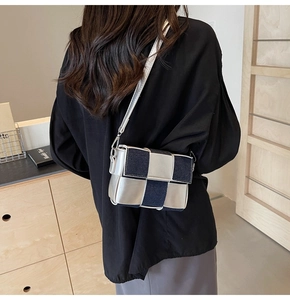 Detail of woven square crossbody bag featuring denim and silver panels with metal hooks