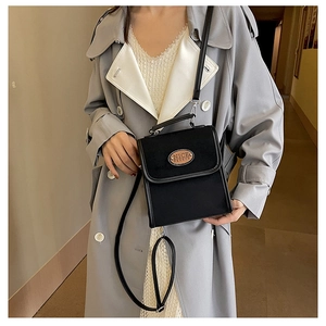 Detail of black rectangular crossbody bag with leather patch and long shoulder strap