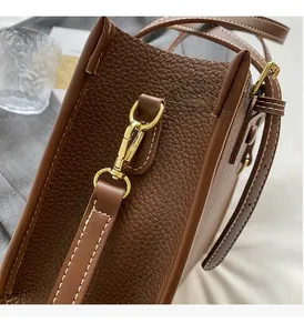 Detail der braunen Leder-Tasche mit goldener D-Ring-Schnalle und weißen Kontrastnähten