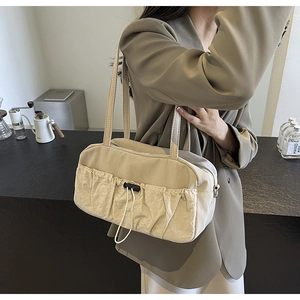 Detail of a beige ruched shoulder bag with drawstring pocket shown in a lifestyle setting