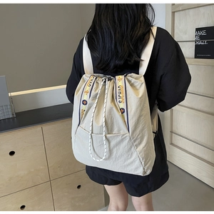 Detalle de la mochila de lona blanco crema con cordón y detalle de correa tejida