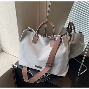Detail of grey nylon tote bag showing leather handles and adjustable woven shoulder strap