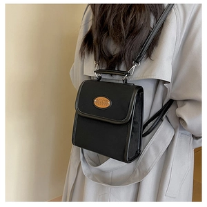 Detail shot of black faux suede backpack featuring a circular brown leather logo patch