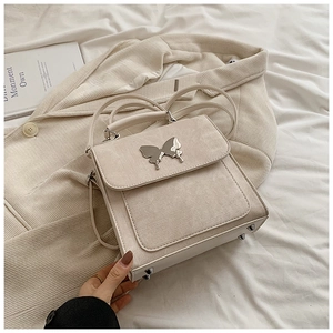Détail d'un sac en tissu blanc crème avec fermoir papillon argenté et clous métalliques