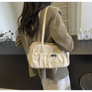 Fashionable beige pleated shoulder bag with large drawstring pocket shown in a cafe