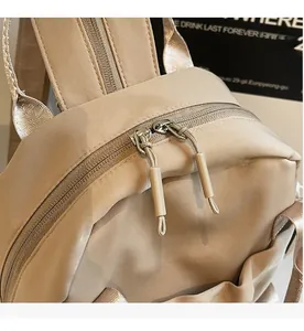 Detail of smooth double zipper closure on lightweight beige nylon backpack for women