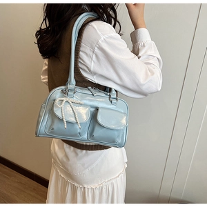 Detail of light blue patent leather bag featuring front pockets and pearl bow charm