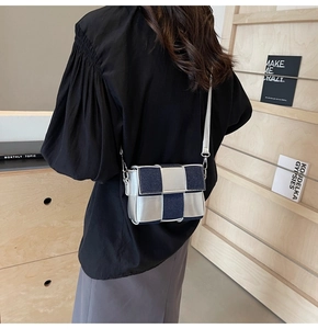 Detail of silver mirror leather and navy denim woven crossbody bag on a model