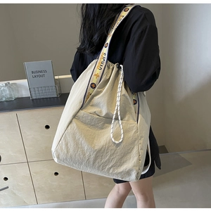 Detalle de bolsa tote con cordón de gran capacidad y correa ancha estampada