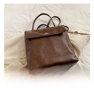 Detail showing brown leather backpack with irregular stitching and silver metal swivel buckle