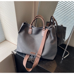Detail of dark grey canvas tote bag with brown leather straps and adjustable shoulder strap