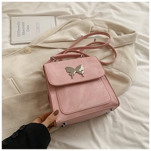Détail du sac à rabat rose avec breloque papillon argentée et texture mate premium