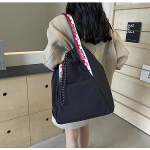Detalle de un bolso tote de nailon negro con una correa tejida de colores SJCHAO